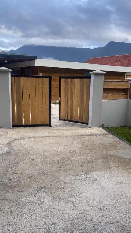 Portail bois et façade bardée devant la montagne · © Le repaire de la mare