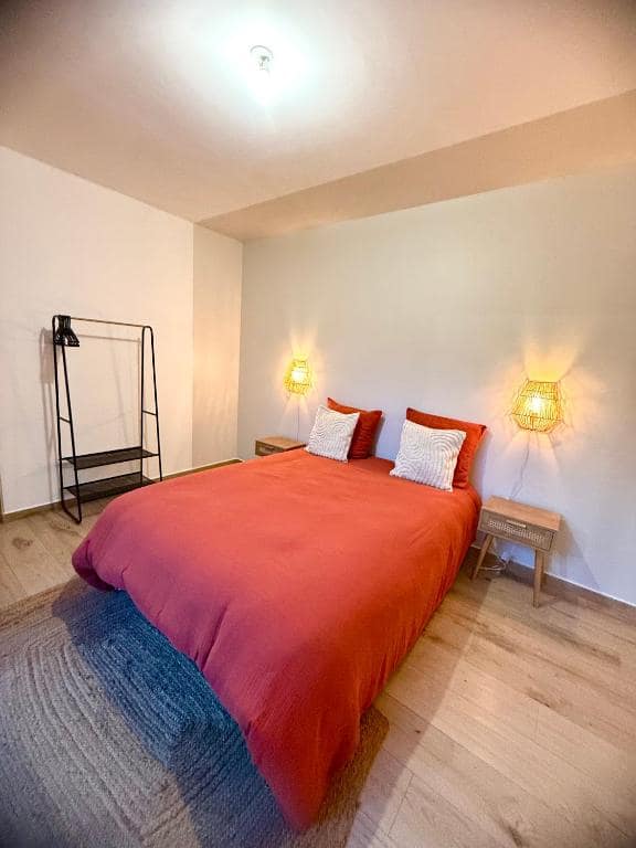 Chambre, couvre-lit corail et appliques en osier · © Le Sounta
