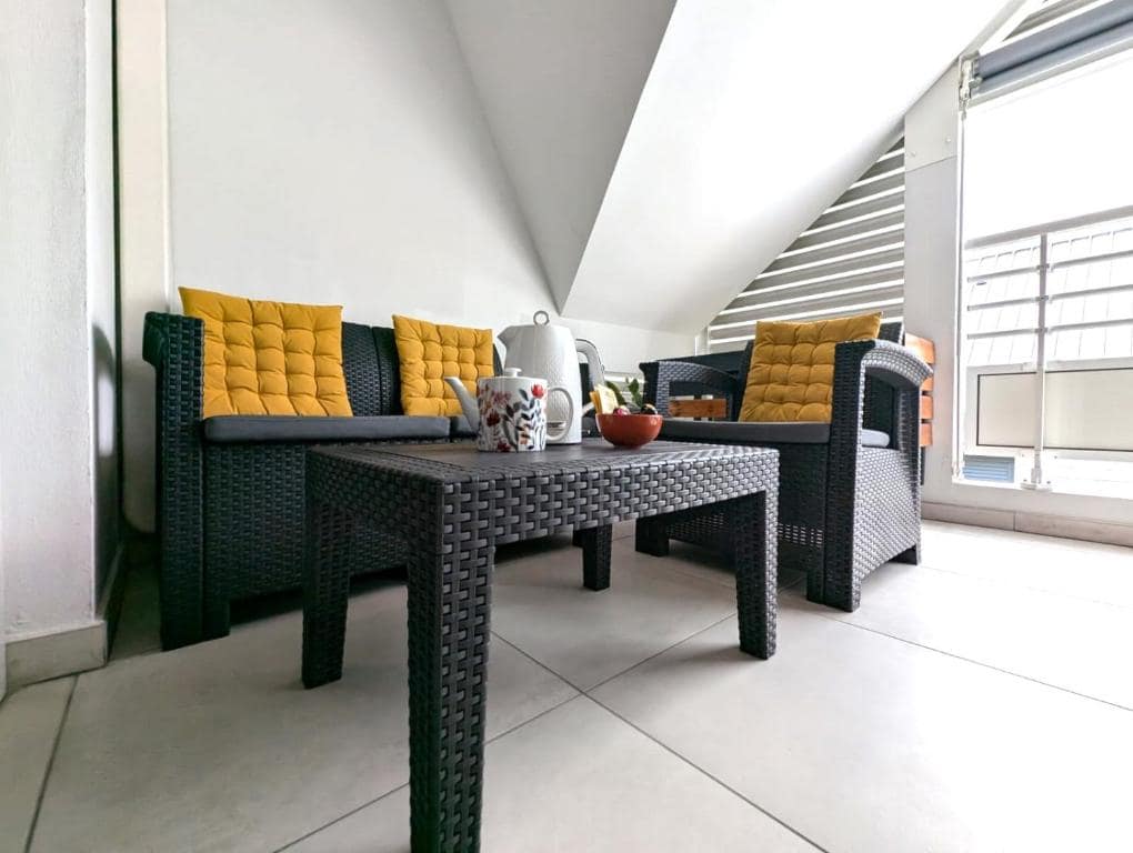 Salon en rotin avec coussins jaunes sous rampant · © Le Zanlik
