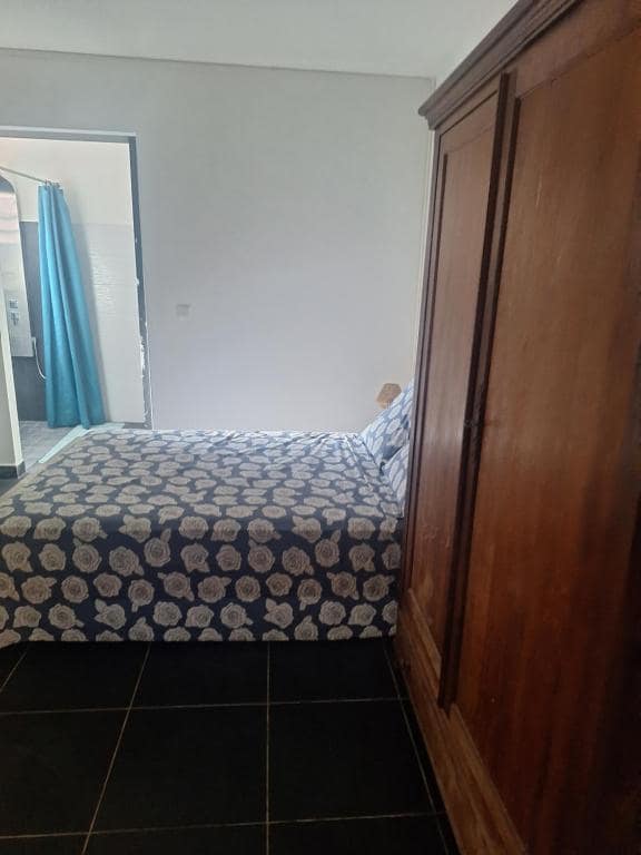 Autre chambre avec grande armoire bois et couvre-lit à motif rosace · © L'écrin de douceur