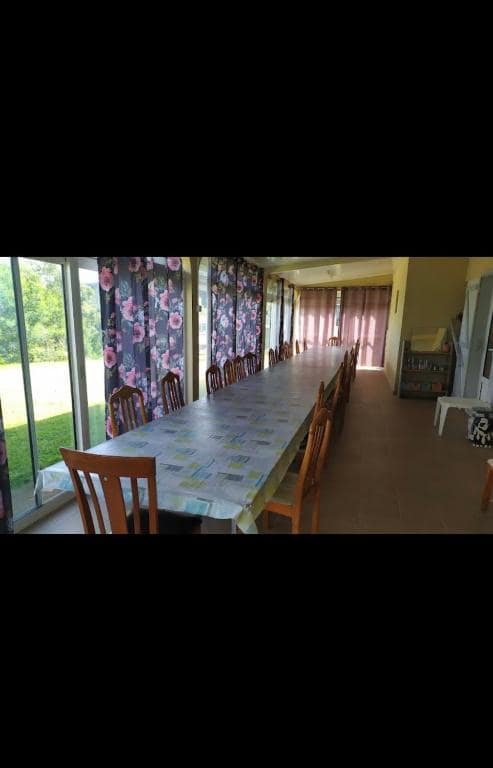 Salle commune vitrée avec grande table pour la table d'hôtes · © Les Acacias