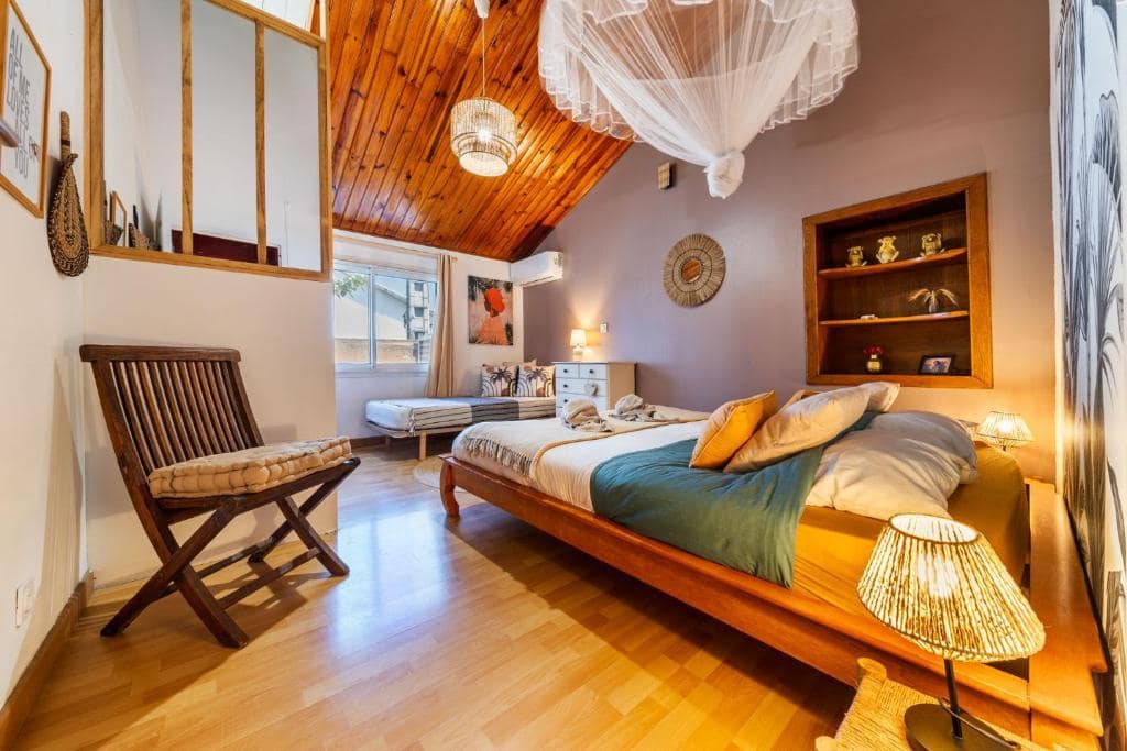 Chambre privée sous charpente bois, lit à moustiquaire · © Les Baroudeurs