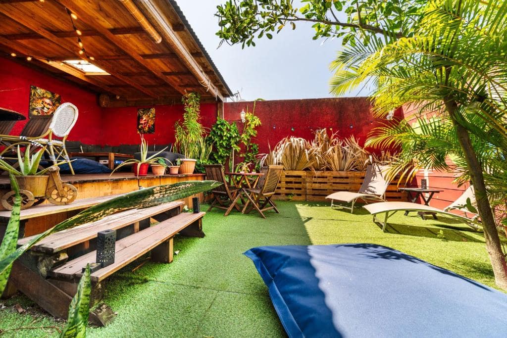 Patio avec bancs en palettes et transats, gazon vert · © Les Baroudeurs
