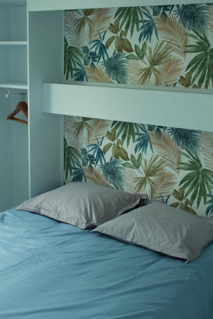Coin nuit et tête de lit au décor végétal · © Les bungalows du château d'Ô