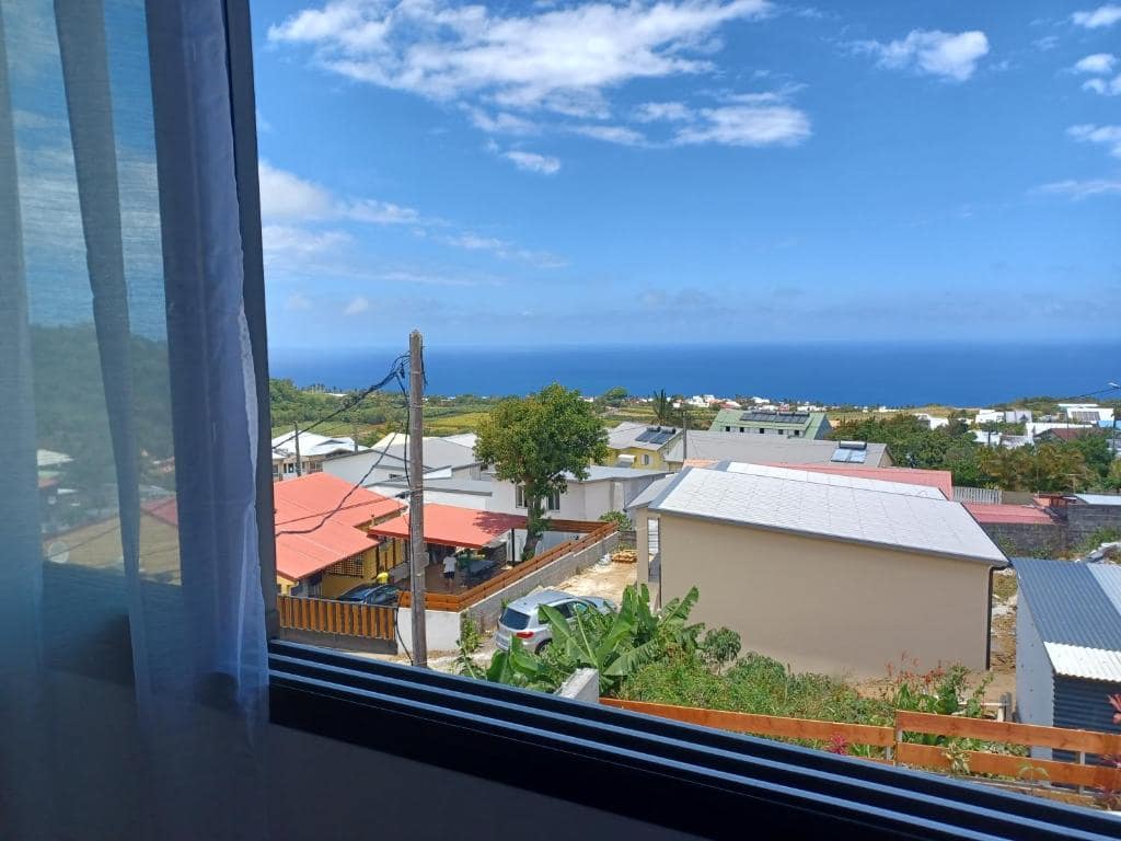 Vue mer par la baie, toits et cocotiers · © Les jumelles