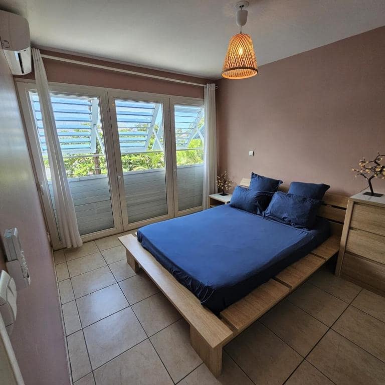 Chambre parents mur mauve avec baies persiennes · © Pieds dans l'eau
