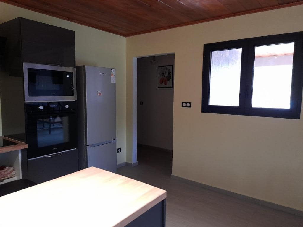 Cuisine équipée, four et frigo intégrés sous plafond bois · © Les Sommets de Salazie