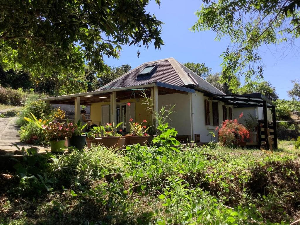 La maison au milieu des cultures, sous son toit noir · © L'îlet Songes