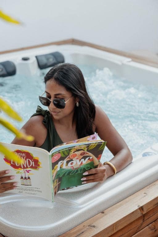 Détail du jacuzzi extérieur, lecture au soleil dans le bassin · © Lodge des palmiers - jacuzzi