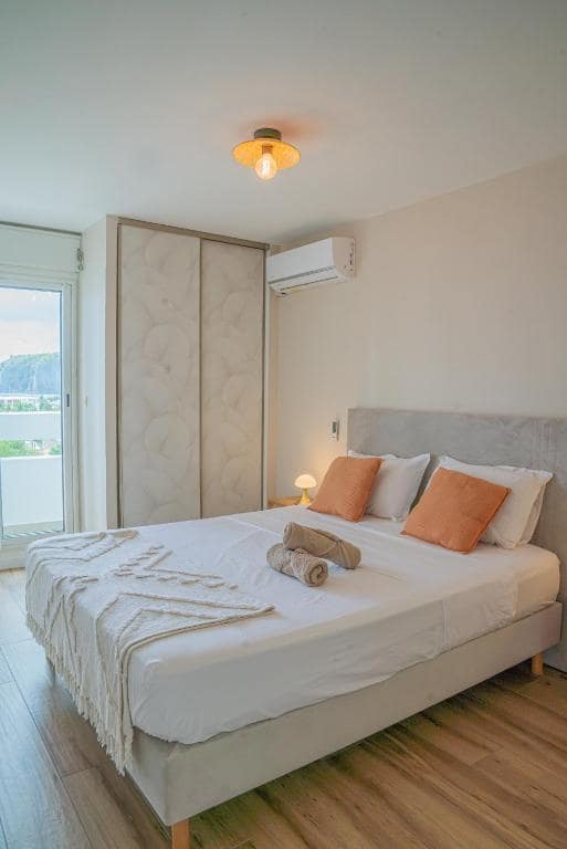 Chambre principale, lit double et coussins orange · © Mafat'appart