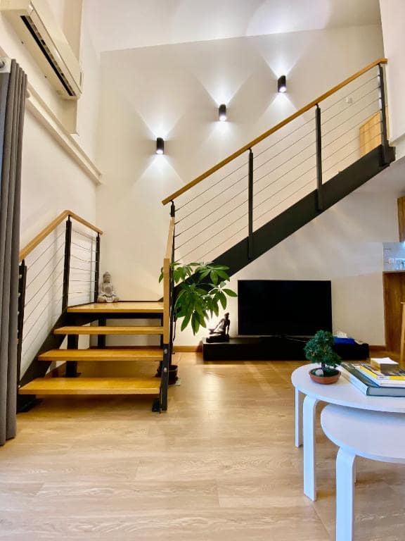 Séjour double hauteur, spots au mur, escalier bois · © Pépite vue cathédrale
