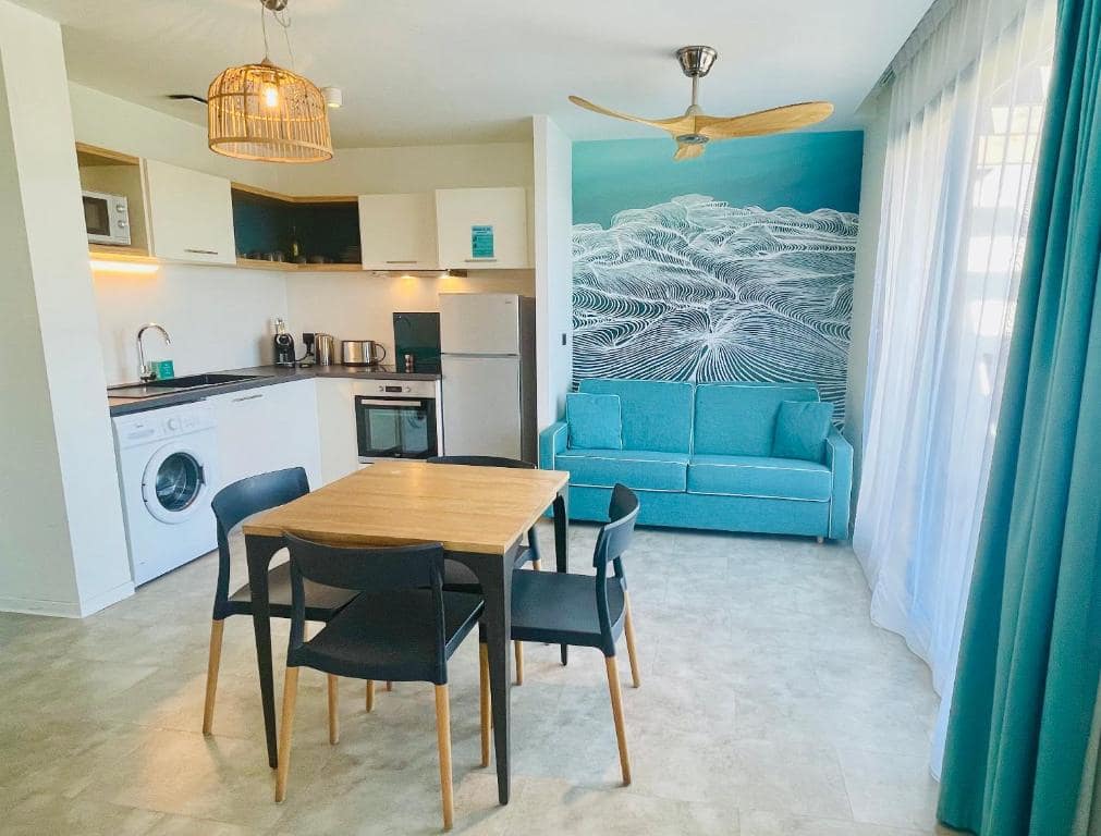 Séjour aparthotel avec kitchenette et fresque vague · © Santa Apolonia