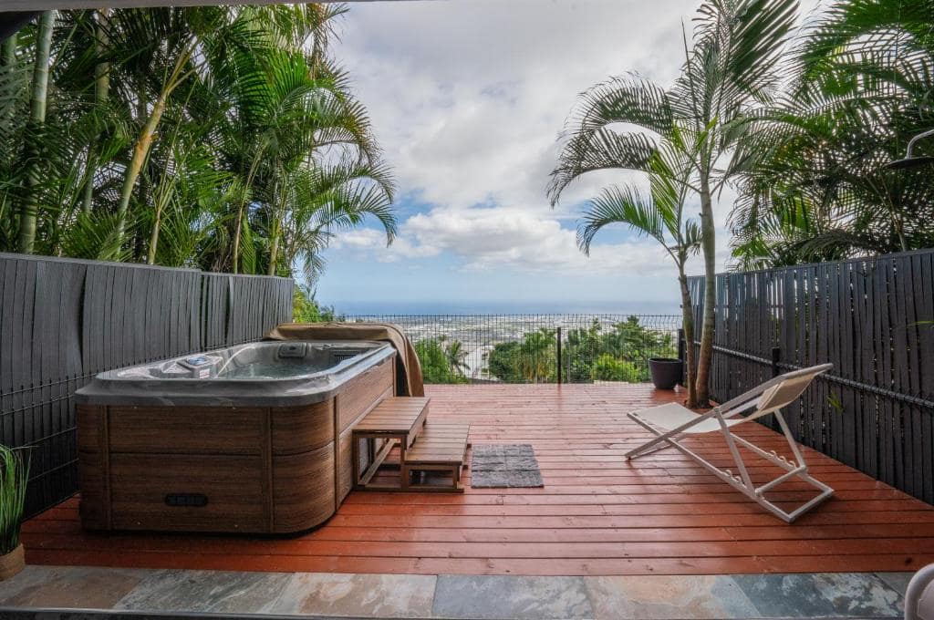 Terrasse en bois avec spa couvert et horizon océan · © Sea View & Spa