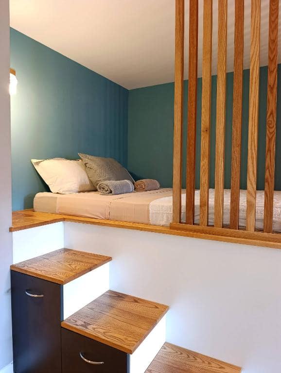 Lit surélevé derrière une claustra en bois · © Studio 56