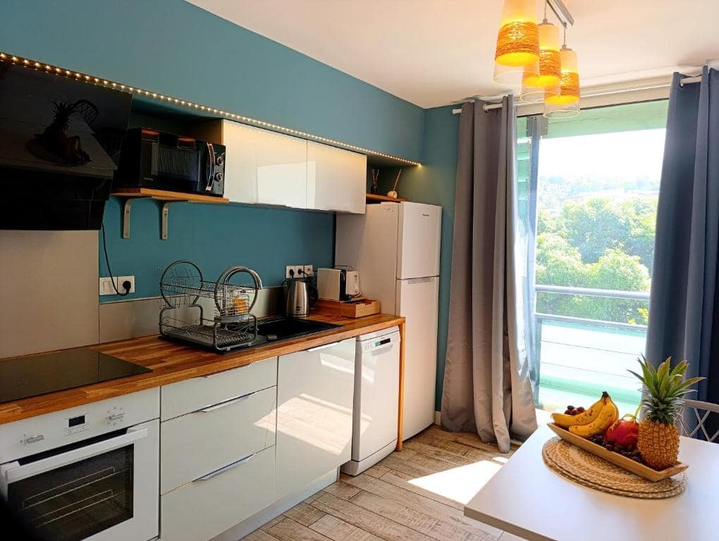 Kitchenette bleu canard face à la baie vitrée · © Studio 56