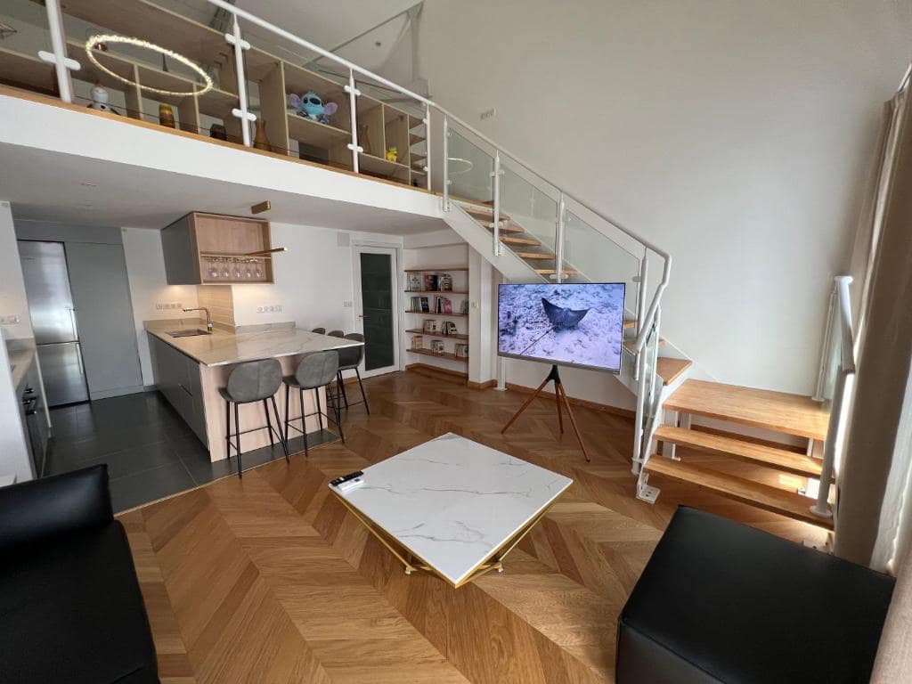 Séjour duplex vu depuis la mezzanine, escalier bois · © Suite Deluxe