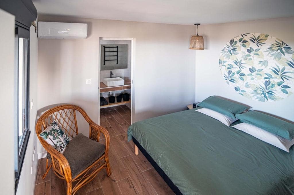 Chambre avec fauteuil rotin et grande tapisserie feuillage · © Sweet Moka