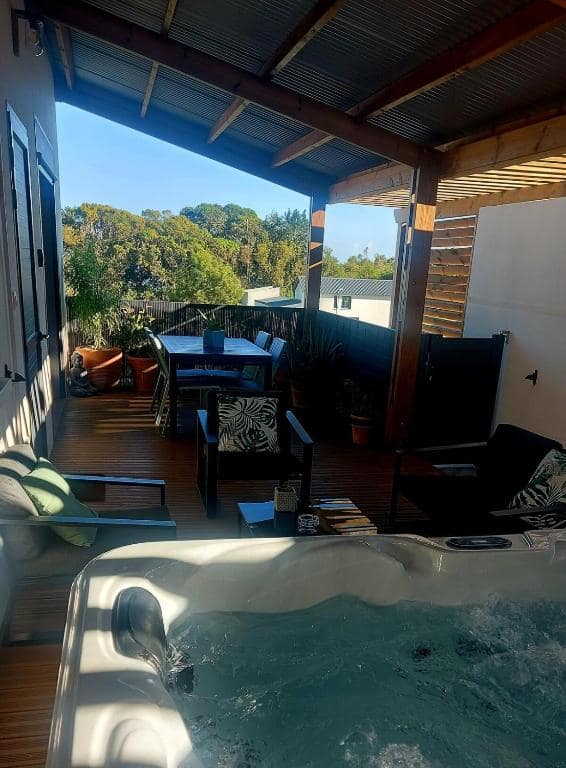 Terrasse bois avec jacuzzi et coin repas à la tombée du jour · © Sweet Moka