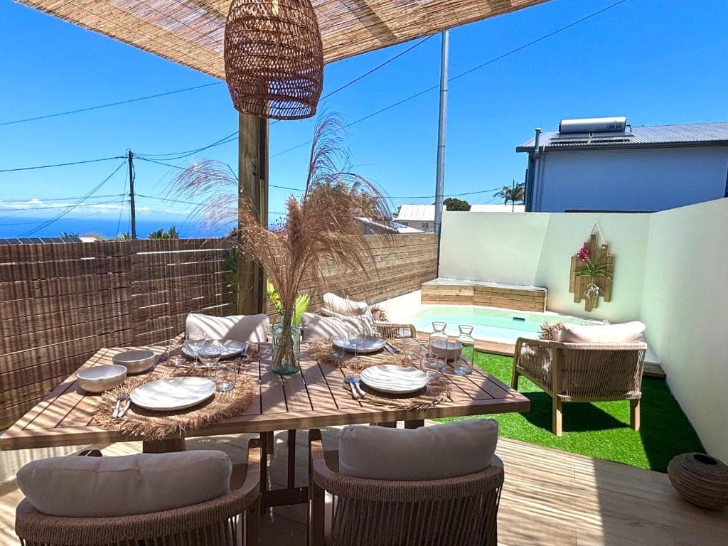 Terrasse bois dressée, piscine et vue mer par la palissade · © Ti Cocoon