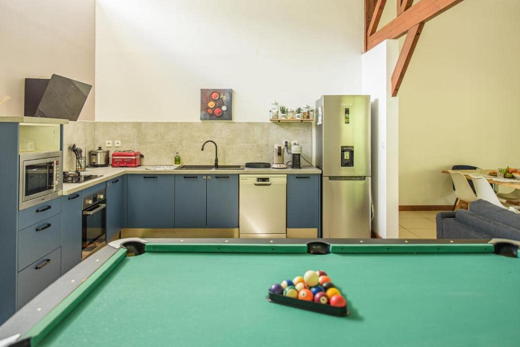 Billard américain au premier plan et cuisine bleue en arrière-plan · © Ti Kaz Bibass