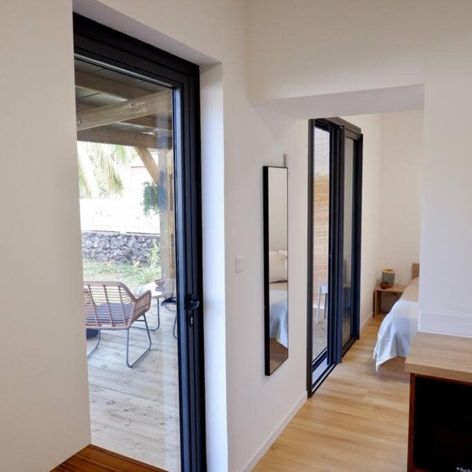 Vue intérieure vers la porte-fenêtre et la chambre attenante · © Ti Kaz