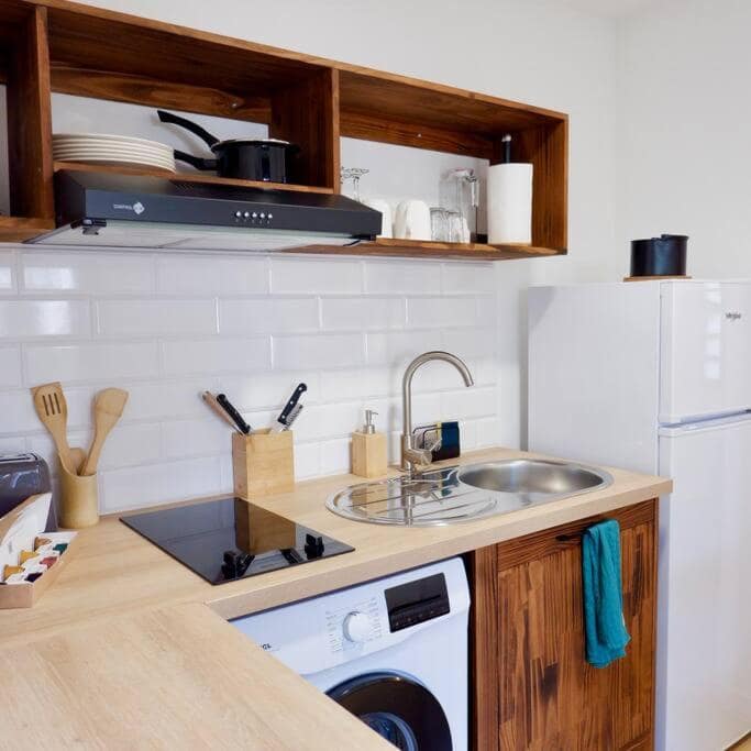 Kitchenette bois clair avec plaques induction et lave-linge · © Ti Kaz