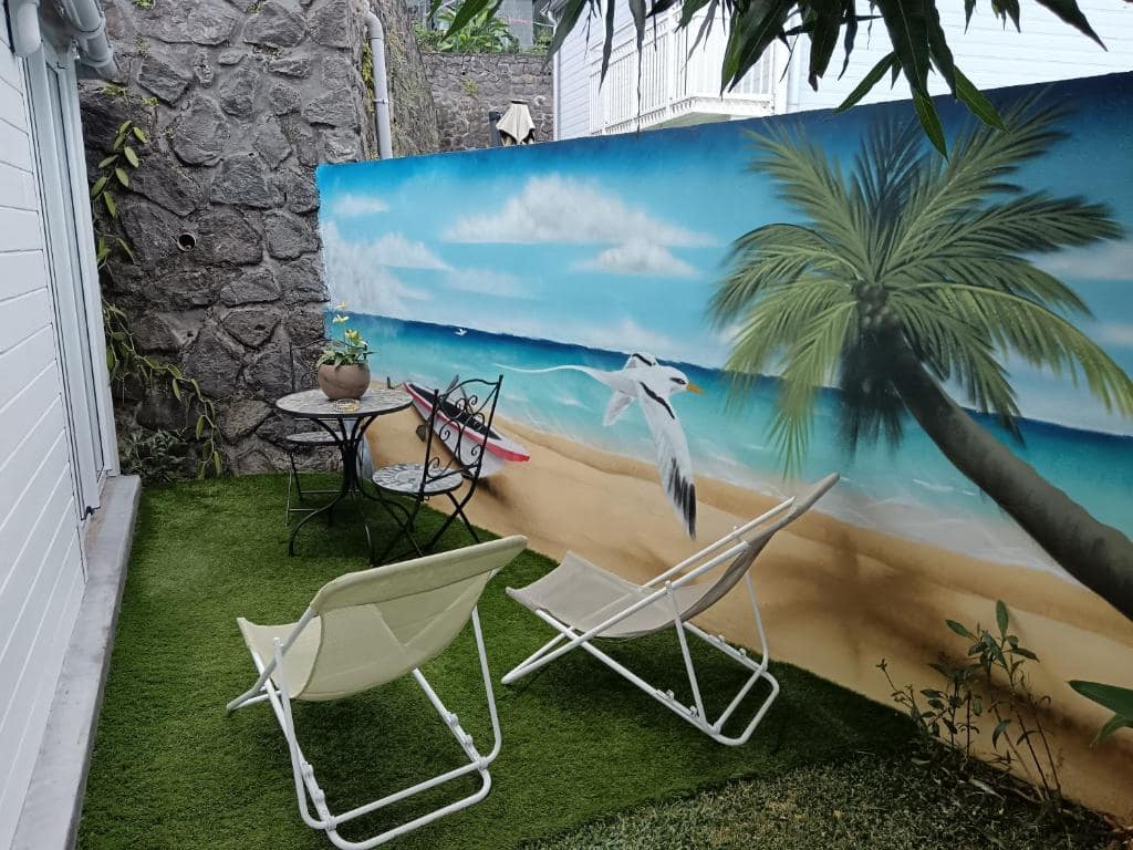 Patio avec fresque murale plage et transats blancs · © Ti Kaz Gigi