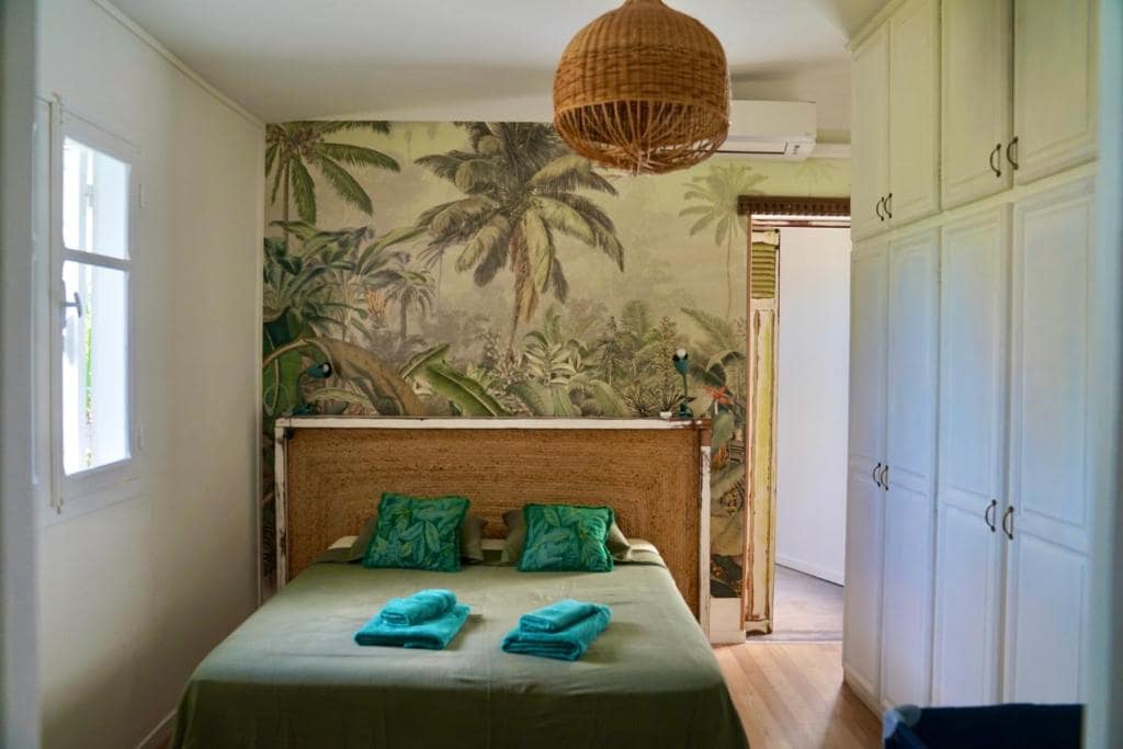 Chambre avec fresque tropicale et tête de lit en jute · © Villa Acacias
