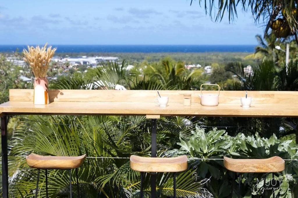Bar haut et tabourets face au littoral, l'océan à l'horizon · © Villa Amara