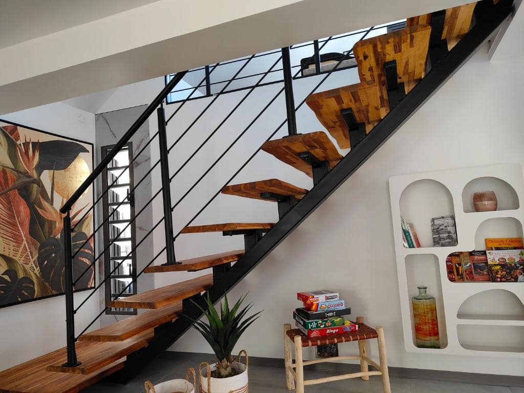 Escalier bois suspendu et coin bibliothèque avec jeux de société · © Villa au coeur de marius