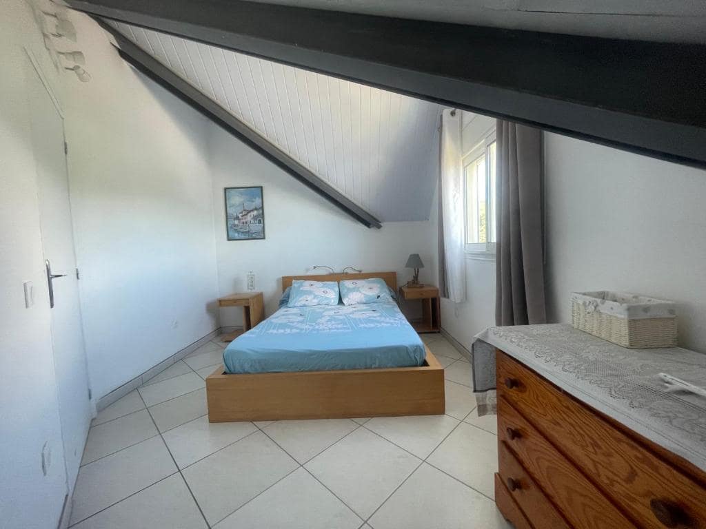 Chambre lodge sous les rampants, tapisserie végétale au-dessus du lit · © Blue Lodge