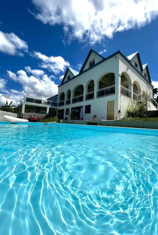 Piscine à débordement vue de face avec la villa en arrière-plan · © Blue Lodge