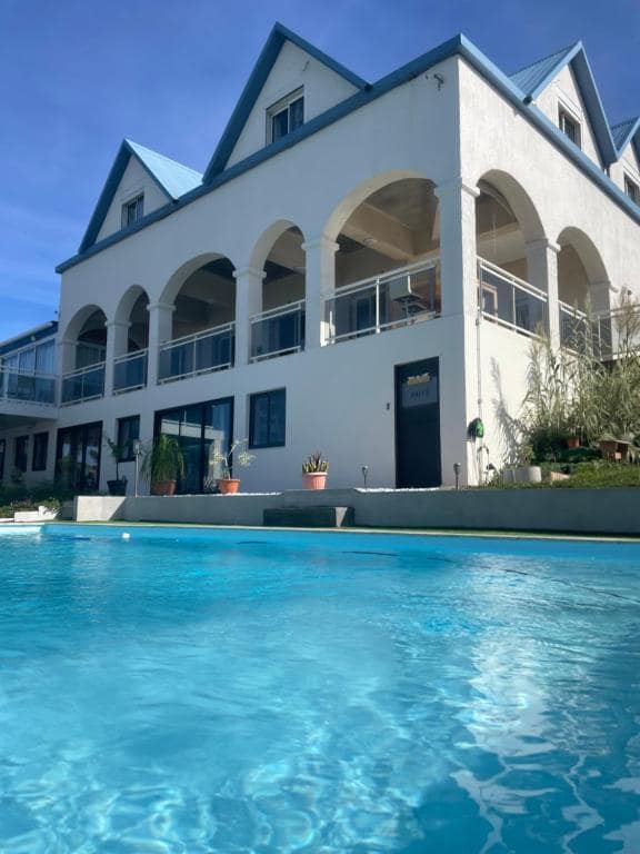 Villa à arches blanches en façade et grande piscine bleue · © Blue Lodge