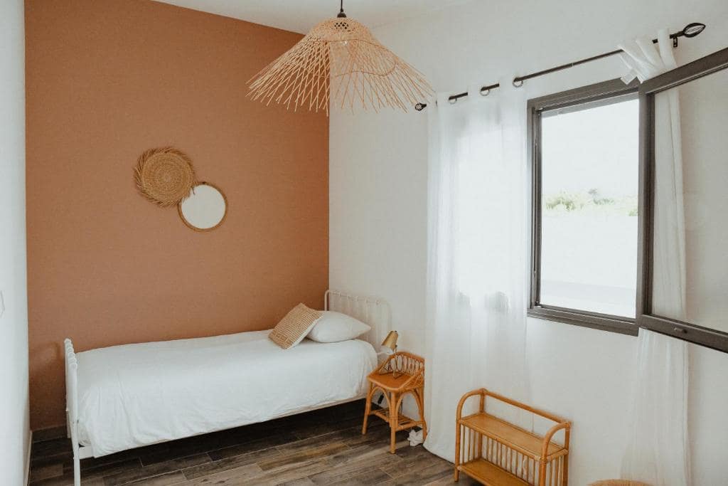 Chambre monoplace, mur terracotta et suspension en osier · © Villa Couleur Nature