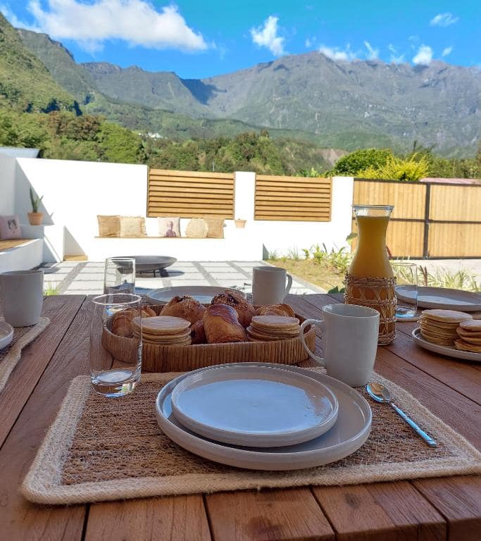 Petit-déjeuner sur table bois, viennoiseries et vue rempart en fond · © Villa Couleur Nature