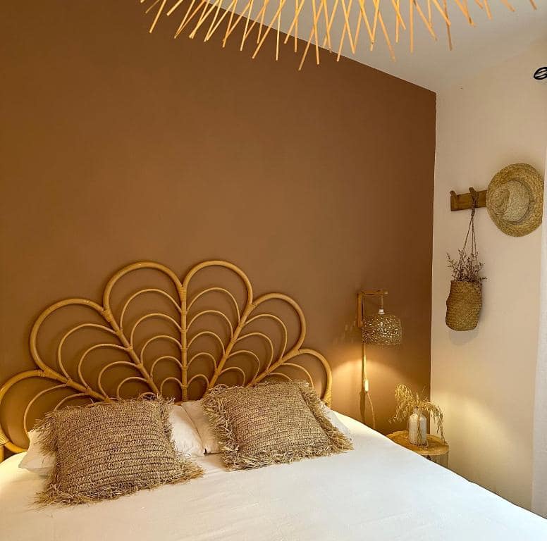 Chambre double, tête de lit rotin en éventail et chapeau accroché au mur · © Villa Couleur Nature