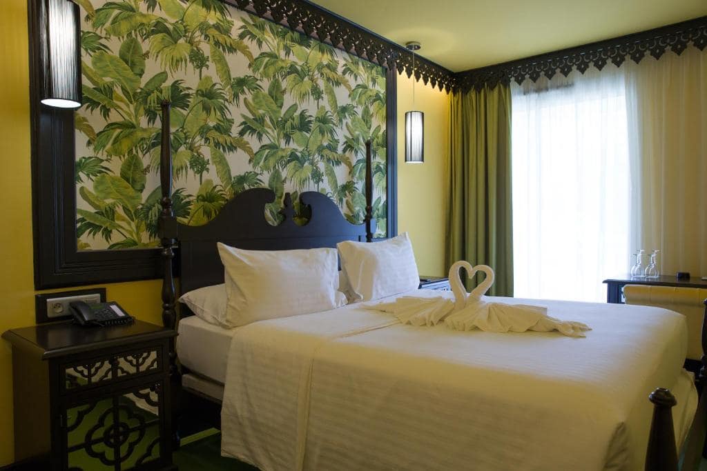 Chambre à papier peint palmiers, moustiquaire romantique · © Villa Delisle Hôtel & Spa