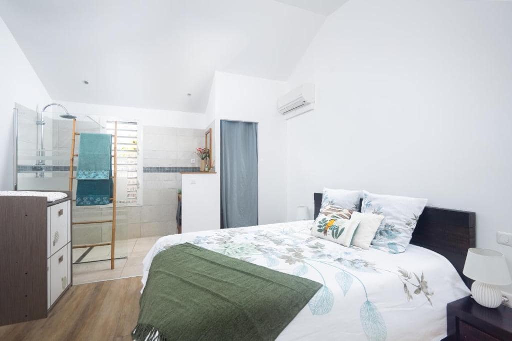 Deuxième chambre avec plaid vert et coin douche ouverte · © Les Lataniers