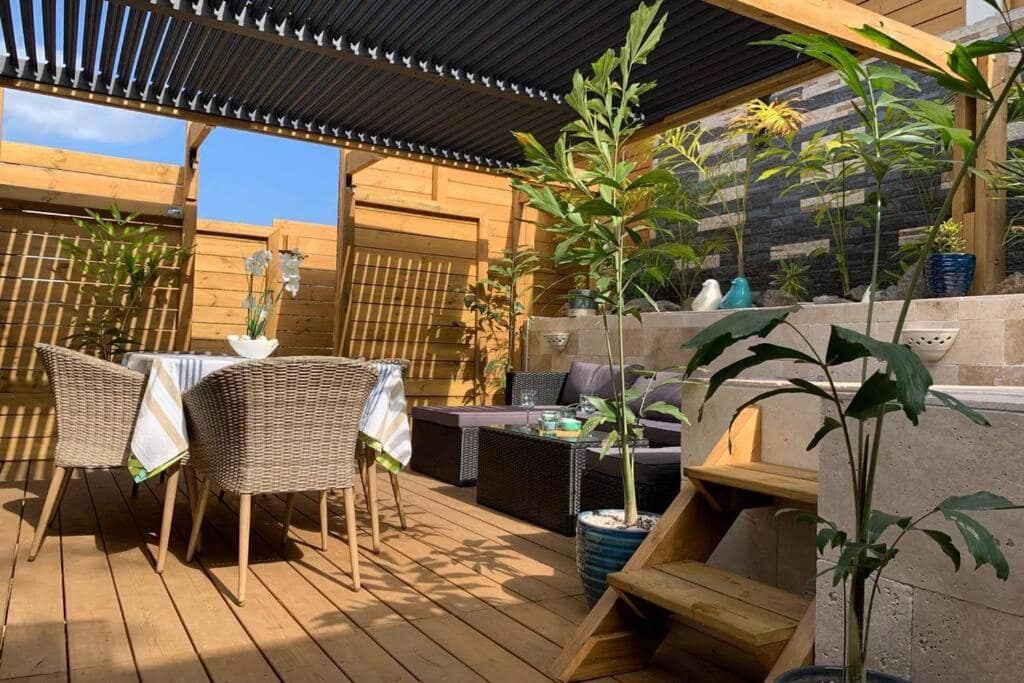Terrasse sous pergola bioclimatique, coin repas et coin salon · © Villa Loret