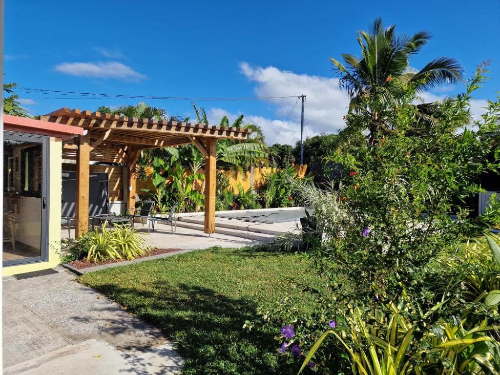 Terrasse arrière avec pergola et petit bassin bordé de pelouse · © La Villa'mie