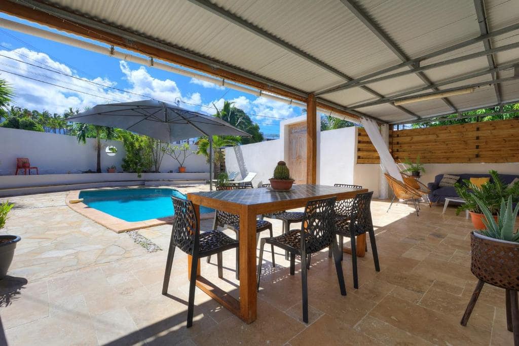 Table de repas sous le carbet en bord de piscine · © La Villa M&M
