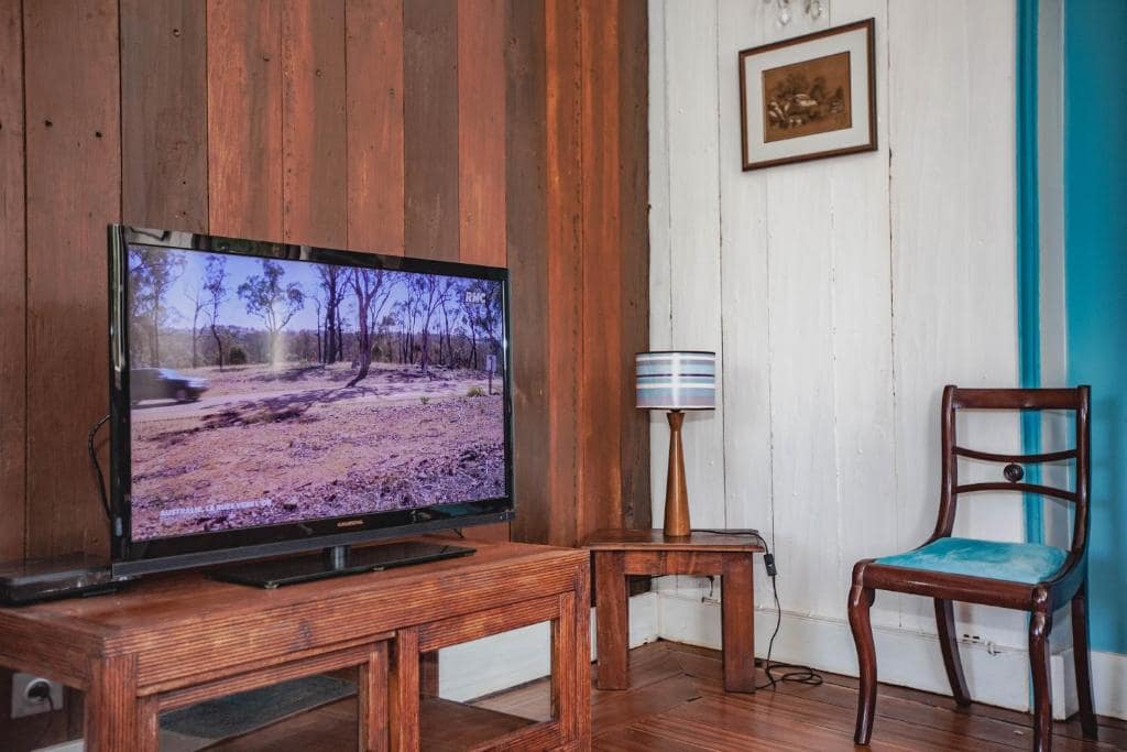 Coin salon TV, bardage bois et fauteuil ancien · © Villa Myriam