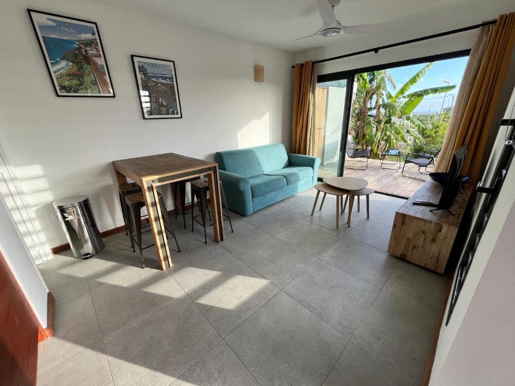 Séjour lumineux avec canapé bleu ouvert sur la terrasse · © Villa neuve vue mer