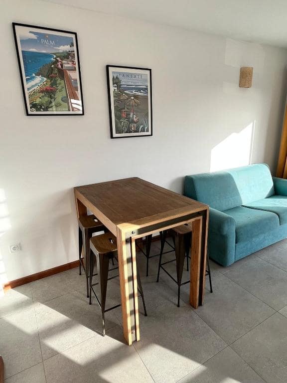 Table haute avec tabourets et affiches Étang-Salé au mur · © Villa neuve vue mer
