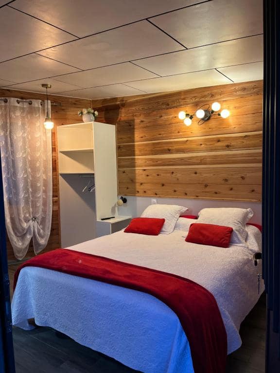 Chambre bois avec grand lit, couvre-lit blanc et plaid rouge · © Villa Niagara avec Spa