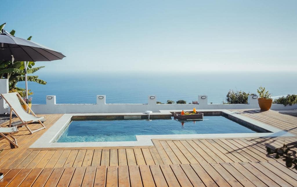 Piscine à débordement sur terrasse bois avec horizon océan · © Villa O Ptit Bonheur