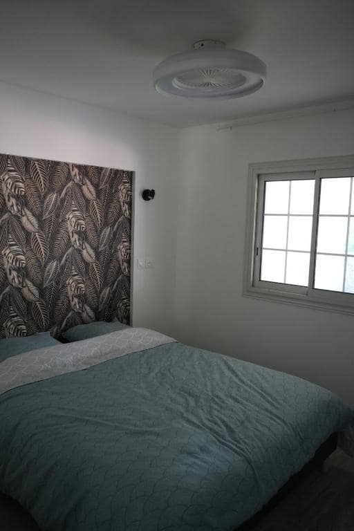 Chambre lit double, tête de lit tapisserie feuillage tropical · © Villa Orchidée