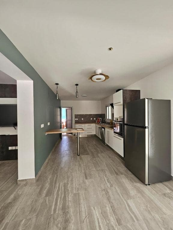 Cuisine équipée avec îlot bois et frigo inox américain · © Villa Orchidée