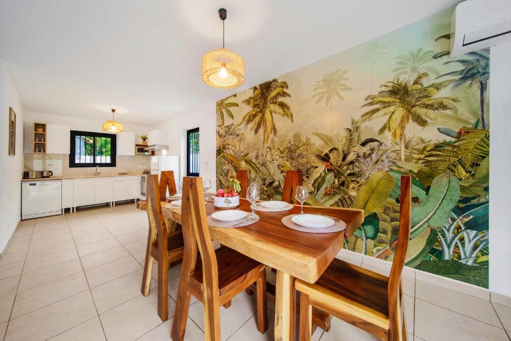 Séjour avec fresque murale de palmiers et table en bois massif · © Villa Takamaka