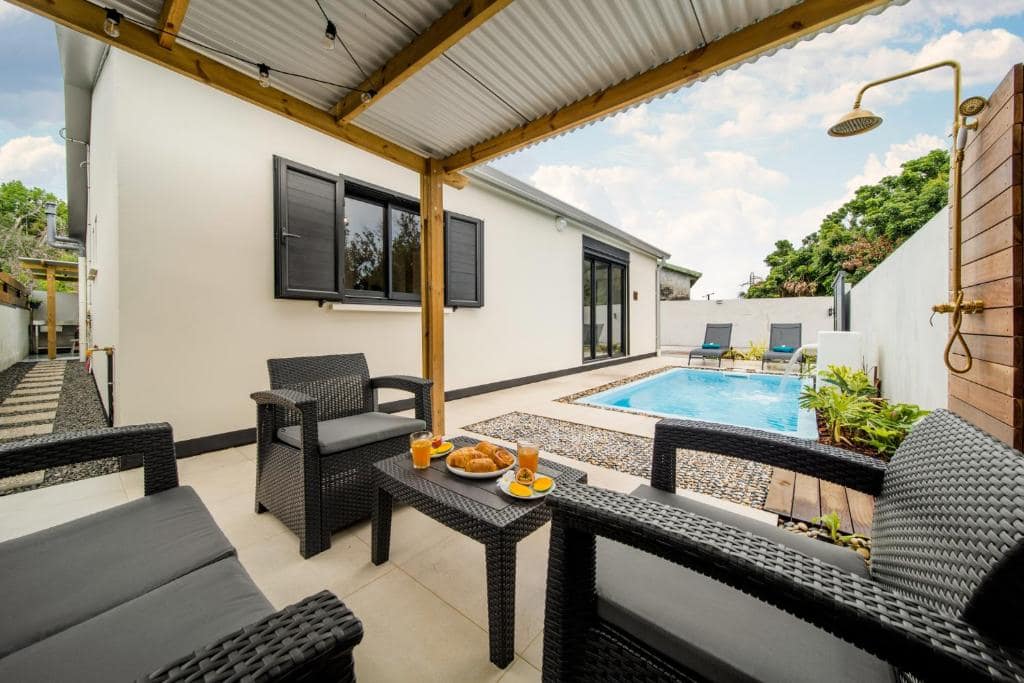 Piscine sous pergola bois et coin salon extérieur · © Villa Takamaka